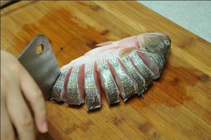 將鱸魚清洗干凈，從脊椎處切斷至腹部，腹部保留1cm左右不要切斷。