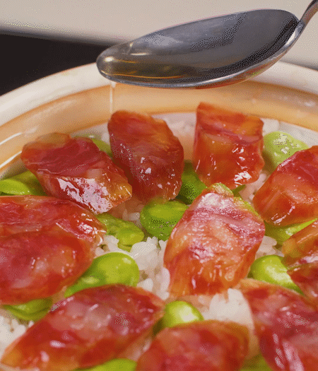 大米出現(xiàn)小孔時(shí)開蓋放香腸，往鍋邊淋入少許油，再燜煮8~10分鐘左右。