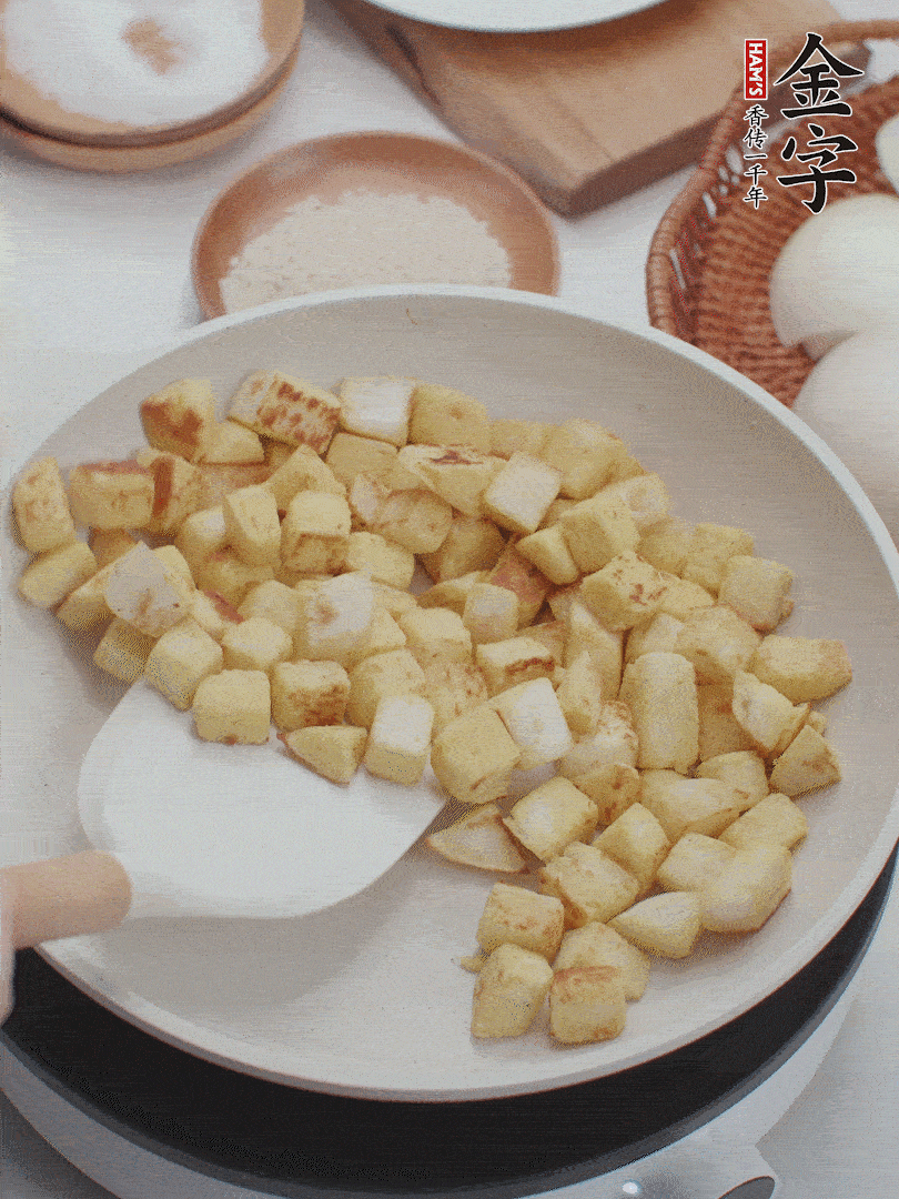 起鍋熱油，倒入饅頭丁，小火煎至蛋液凝固定型再翻面，饅頭丁部煎至金黃時(shí)盛起待用。