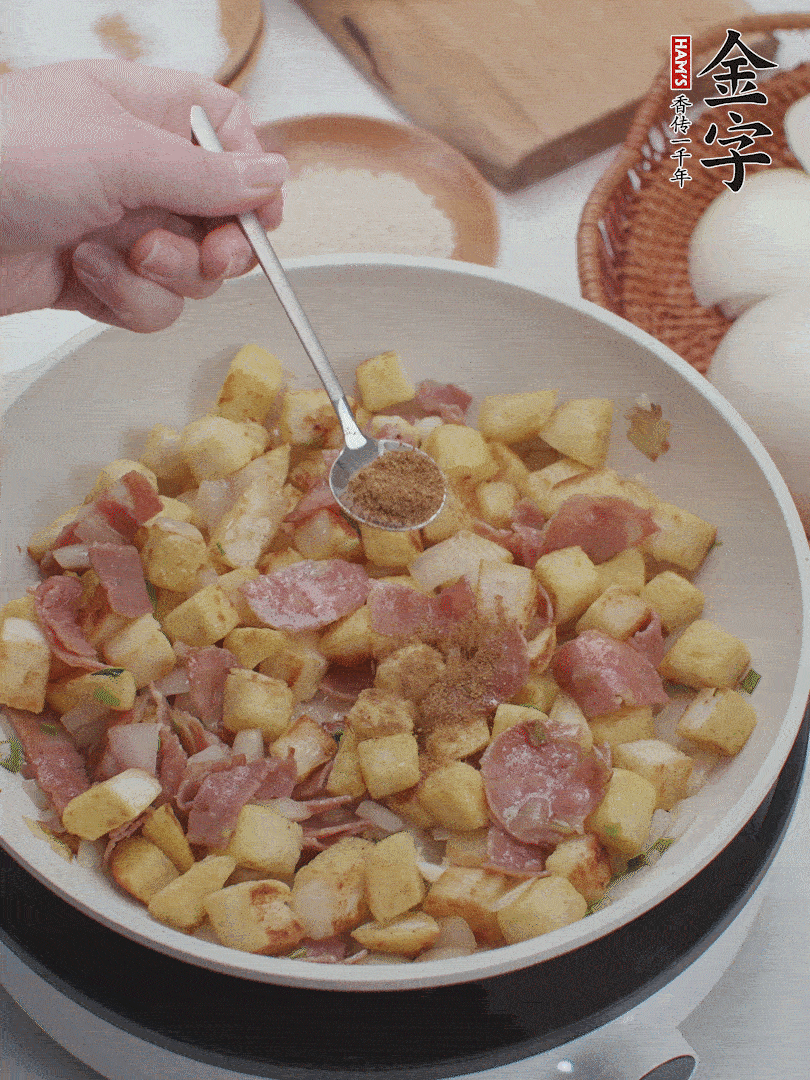 起鍋少油，煸香洋蔥丁、蔥白，加入金字培根火腿翻炒幾下，再加入饅頭丁、1小勺孜然粉、少許鹽翻炒均勻并鋪平。