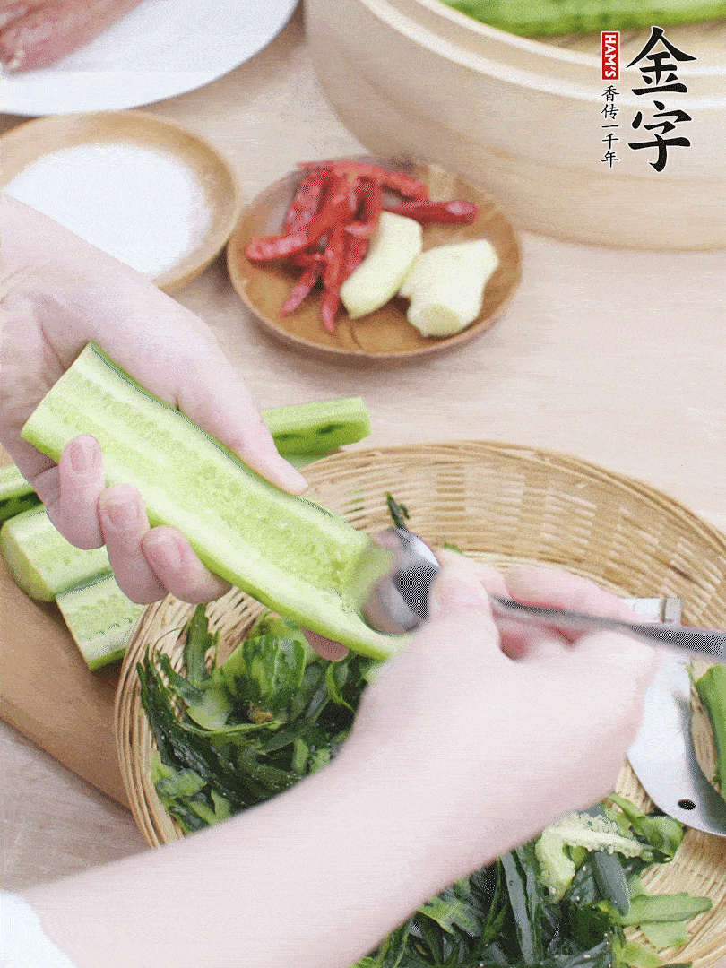黃瓜削皮，對半切開，勺子挖去內(nèi)瓤，斜刀切片。青蒜斜刀切段。