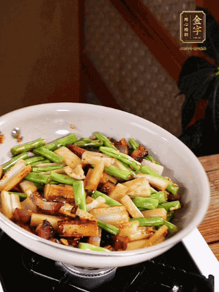 油熱下蒜末、干辣椒、醬肉煸炒出香味，依次下藕條、豆角翻炒均勻